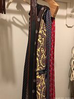 Photo showing multiple neckties hanging on wooden hangers in a closet, highlighting colors and patterns including paisley and geometric designs.