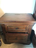 Front view of the Universal Furniture nightstand showing two drawers, one partially open, with dark wood finish and round metal knobs.