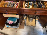 Open drawers showing multiple kitchen utensils: spatulas, peelers, knives, and spoons organized in compartments.