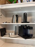 Shelf view showing all items including Nespresso machine, kettle, cups, saucers, plates, and glasses.