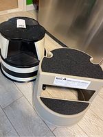 Two rolling step stools shown side by side highlighting stepped carpeted surfaces and sturdy plastic frames.