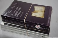 Photo showing the six sealed books in their original wrappers stacked, including The History of the English Language (2 volumes), English in America, and Classics of Russian Literature (3 volumes).