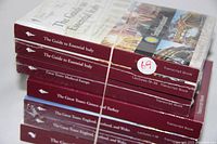 Stack of seven maroon-banded Great Courses transcript books, sealed in original plastic wrap with rubber bands. Titles visible include 'The Guide to Essential Italy', 'Great Tours Medieval Europe', 'Great Tours Greece and Turkey', 'Great Tours England Scotland and Wales', and 'Great Tours Washington DC'.