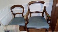 Photo showing 3 armless balloon back chairs and 1 captain's chair with arms, all have blue upholstered seats and wooden frames with scratches.