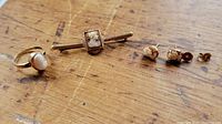 Ring, bar brooch, and pair of earrings on wooden surface