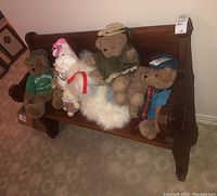 Front view of the wooden church pew showing multiple teddy bears and plush toys sitting on it.