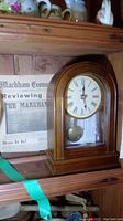Bulova wooden mantel clock on a shelf beside and behind a framed 1956 Markham Economist and Sun newspaper clipping