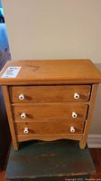 Front view of vintage craftsman sample dresser showing three drawers and white ceramic knobs.