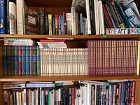 Bookshelf with upper shelf containing various educational and literature books in hardcover and paperback, including art-focused titles.