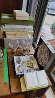 View from above showing stacked stationery paper sets on the left, two glass tea light goblet holders in the center, the boxed china set on the right, and two white soap bars in front of the china box.