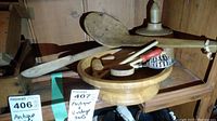Multiple wooden child-size kitchen utensils displayed in a wooden bowl with price tags visible. Includes rolling pin, meat mallet, cookie press, and spoons.