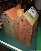 Two rustic folk art wood houses side by side, showing orange and yellow painted roofs, with black painted windows and chimneys.