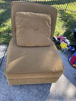 Front view of the brown slipper style accent chair with matching cushion, showing upholstery and condition.