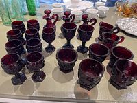Overview of the collection showing various red glass goblets, small glasses, and decanter bottles with stoppers in Cape Cod pattern.