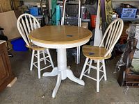 Full view of pub height bistro table and 2 matching chairs, showing wood finishes and white bases