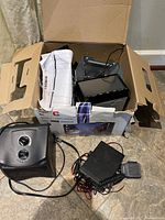 Box with all items: portable space heater, car DVD receiver, and CB radio with wires and papers.