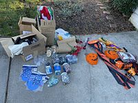 Wide view of the full lot showing boxes, burlap rolls, blue star-patterned craft packets, jars of mosaic glass tiles, and Halloween fabric decorations.