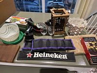 Photo showing all items on a kitchen table including garlic press, lantern, Heineken bar pad, chip and salsa dish, ankle weights, glasses, cutting boards, and candle set.