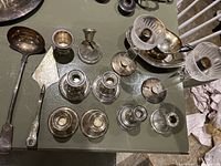Overview of all silver and silver plated items including candle holders, ladle, pie server, and gravy boat.
