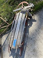 Photo of vintage wooden sled showing wooden slats and red metal runners with rust.