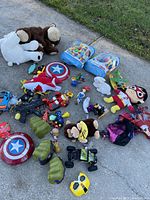 Overview of assorted toys including shields, plush, toy guns, airplane, and figurines scattered on the ground.