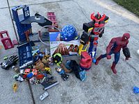 Overview photo showing assortment of toys including the large Spiderman figure, toy robot, several small cars, playset parts and various small figures and accessories.