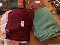Overview of fleece throw, wool blankets stacked together showing colors and condition including holes and pilling