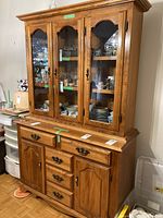 Front angled view of solid maple buffet and hutch with contents inside hutch visible through glass doors
