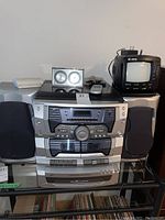 Front view of Emerson stereo system with two speakers, Curtis TV, clock, and remote on top