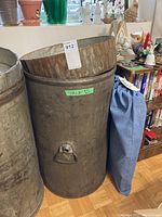 Full view of cylindrical metal grain barrel with removable lid on top, measuring 18 by 30 inches, shows aged metal and rust spots.