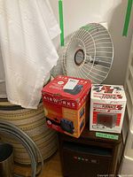 Photo showing four heaters: a Presto HeatDish electric heater with grille, AirWorks ceramic heater in box, Micro Furnace heater box, and Duraflame heater box on side table