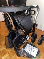 Side view of black Evolution Xpresso Lite Mini rollator with front basket and soft basket accessory placed below showing mesh and fabric construction.