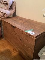 Rustic pine wood blanket box, showing front and top surfaces with wood grain and lid opening feature.