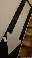 Full view of metal arrow sign showing black arrow pointing down on white background with metallic edges and mounting holes