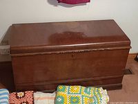 Front view of the closed cedar chest showing the reddish-brown wood finish and base molding.