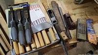 Set of lathe chisels on tray with various files, rasps, and hand planers laid on a wooden surface