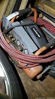 Overall view of compressor unit with orange frame and coiled red hose.
