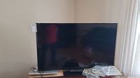 Insignia flat-screen TV with remote on stand.