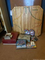 Full view of wooden game board with accessories including cards, marbles, and dice in boxes and bags arranged in front.