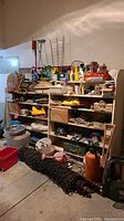 Wide shot showing shelving unit with garden tools, light fixtures, power cords, containers, and other equipment.