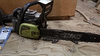 Photo of the full Poulan gas chain saw showing the 18 inch ECHO branded saw bar and black handle on a wood surface.