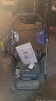 Full view of Kobalt electric pressure washer with handle, power cord wrapped on side, spray wand attached, and manual on top.