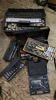 Photo showing multiple toolboxes and cases open with assorted ratchets, sockets, wrenches, and hand tools visible inside them.