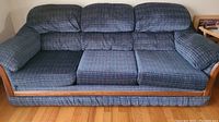 Full front view of three-seat sofa showing textured blue-green velour upholstery and wood trim on arms and base.