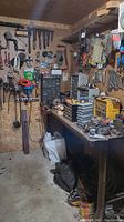 Tools and hardware displayed on pegboard and workbench including various wrenches, saw blades, grinder wheels, and storage containers.
