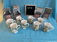 Full view of all eight cups arranged in two rows with their original boxes in the background on a blue backdrop