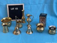 Photo showing nine assorted brass items including brass bells, pitchers, pots, and a boxed brass bell.