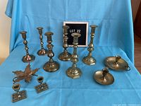 Full group display of all brass candle holders and candle snuffer on blue background