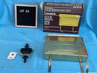 Photo showing lot number board with the unopened brass mailbox box, the mailbox unit, black and brass door knocker, and instruction sheet.