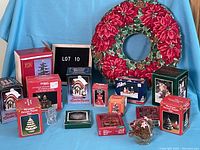 Front view of Christmas wreath with various boxed Christmas decorations arranged in front on blue background